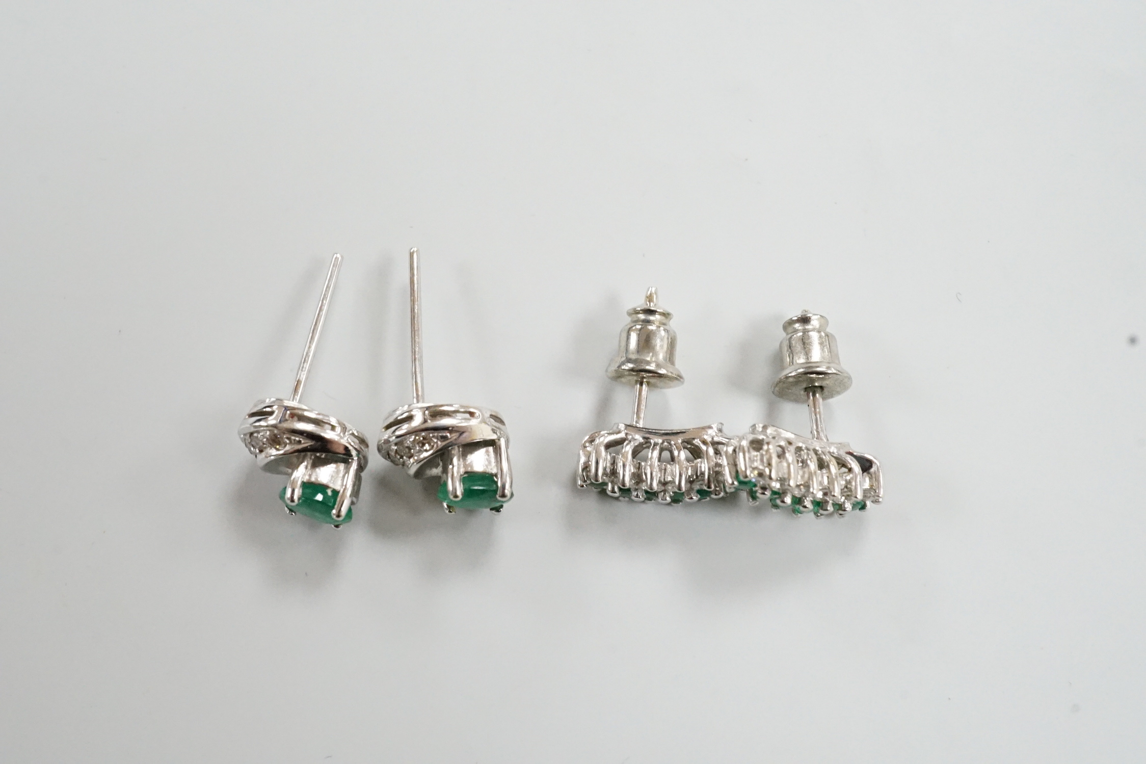 Two moderns pairs of emerald and diamond set ear studs, including white metal two row and 14k oval cut single stone and diamond chip, 7mm, gross weight 5.6 grams.